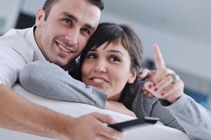 Relaxed young  couple watching tv at home in bright living room